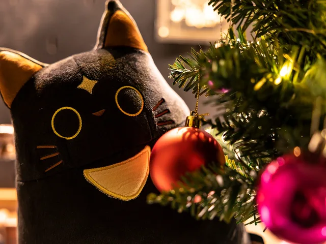 Cafemi plush beside a decorated Christmas tree